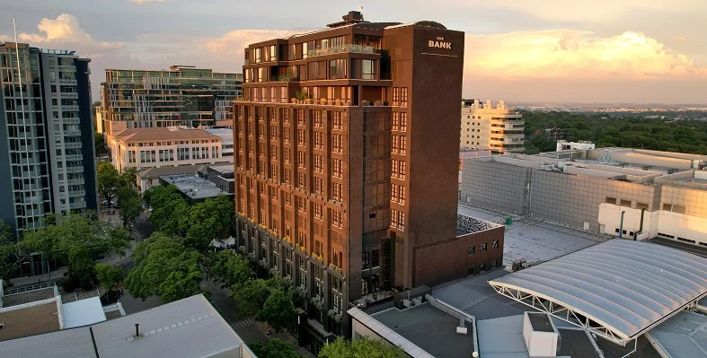 A wide shot of the Hyde Johannesburg hotel in South Africa against a sunset.