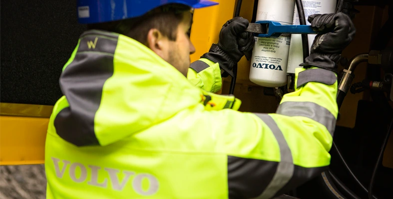 A Volvo technician replacing equipment in a piece of construction machinery.