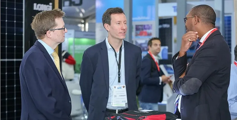 Three aef attendees discussing at a company stand. 