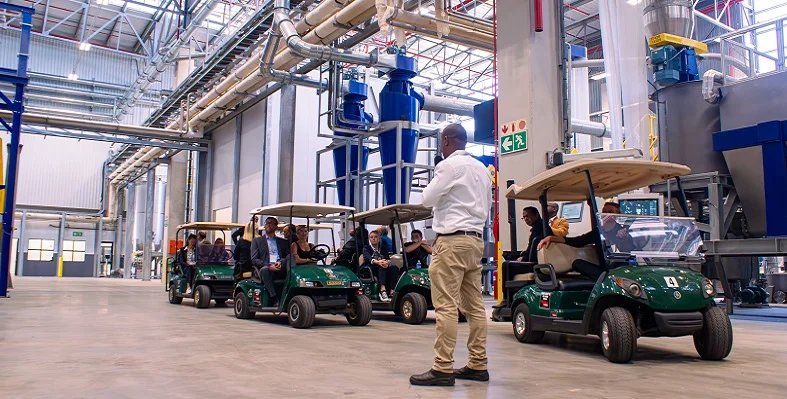 A picture from the inside of the ALPLA facility with guests being shown around on golf buggies.