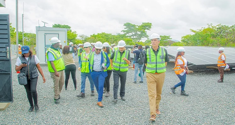 Leaders of the involved organisations walking through a concrete area with solar panels in the background.