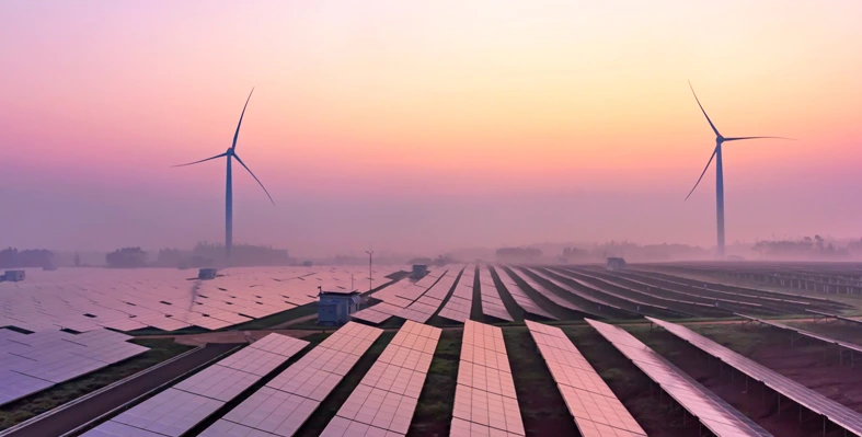 Wind turbines in the background with solar panels in the foreground. 