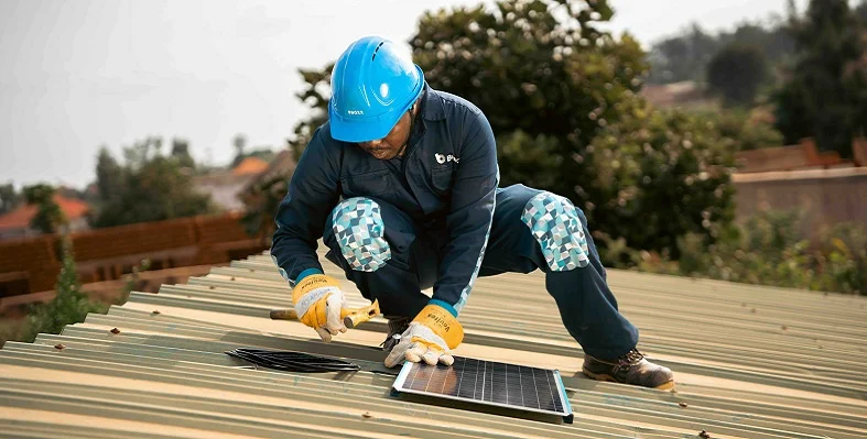 A Bboxx employee installing a solar panel onto a roof. 