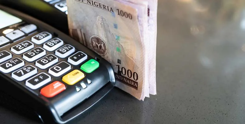 Nigerian naira stacked up next to a card reader.