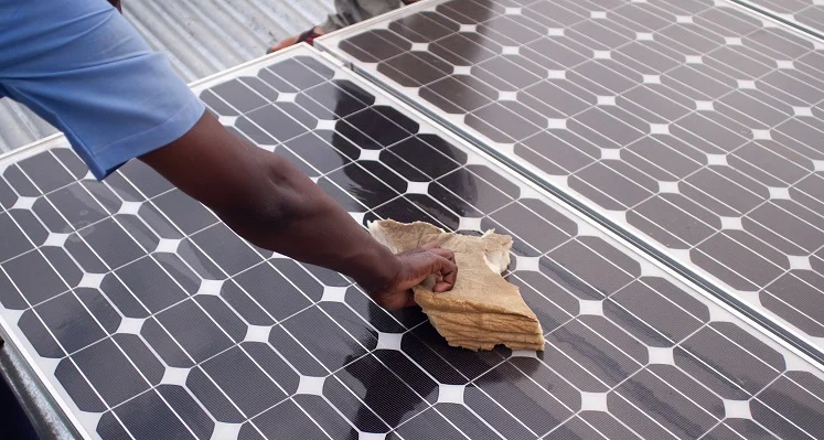 A man wiping down a solar panel with a cloth. 