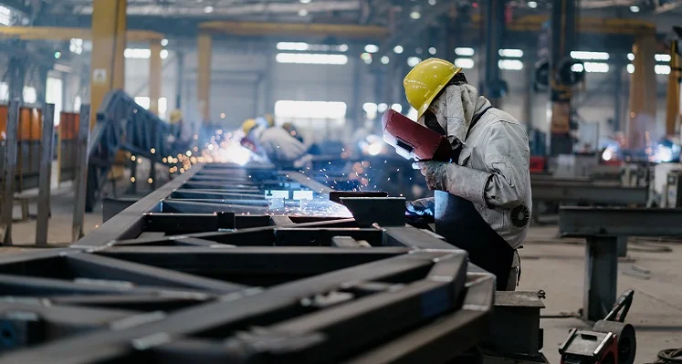 A worker welding iron on a manufacturing facility floor. 